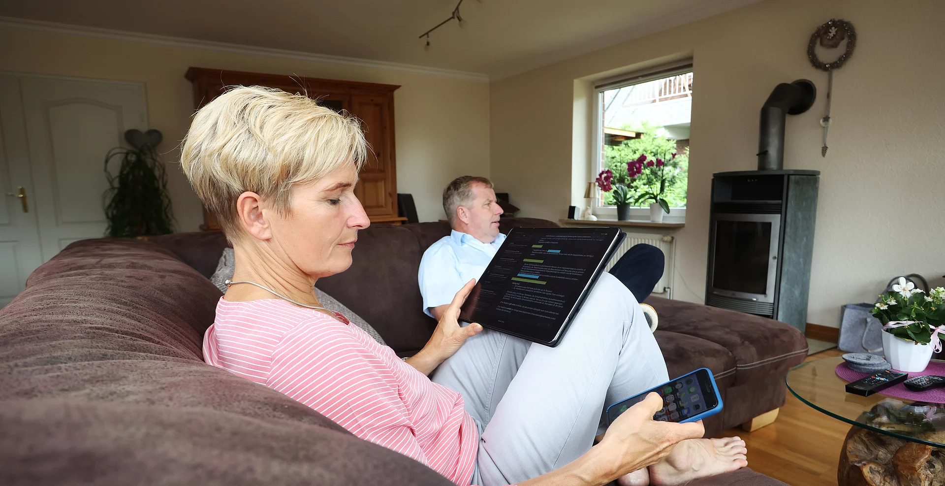 Familie auf der Couch bei der Nutzung von TV, Notebook und Handy