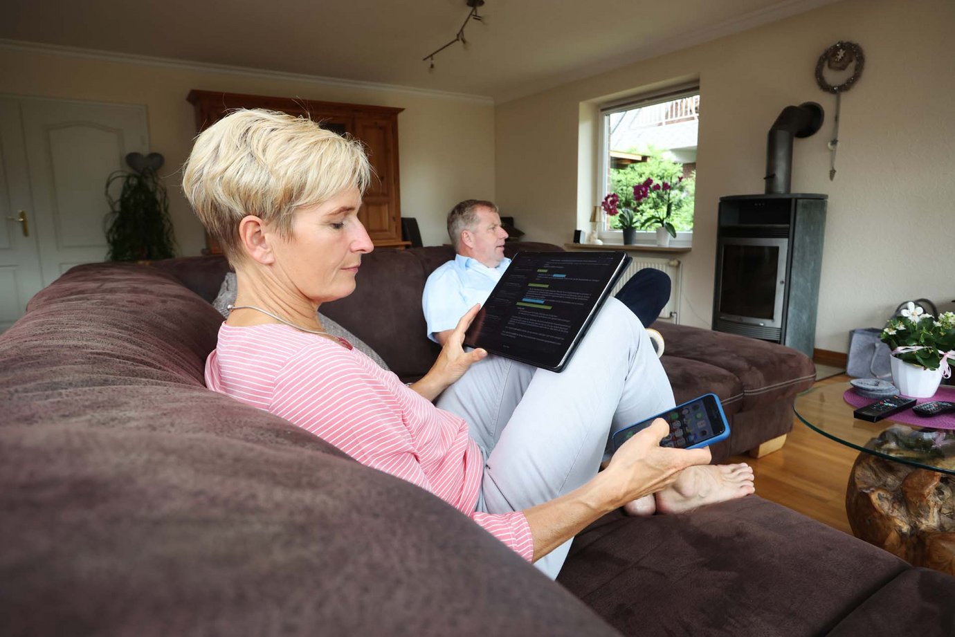 Familie auf der Couch bei der Nutzung von TV, Notebook und Handy