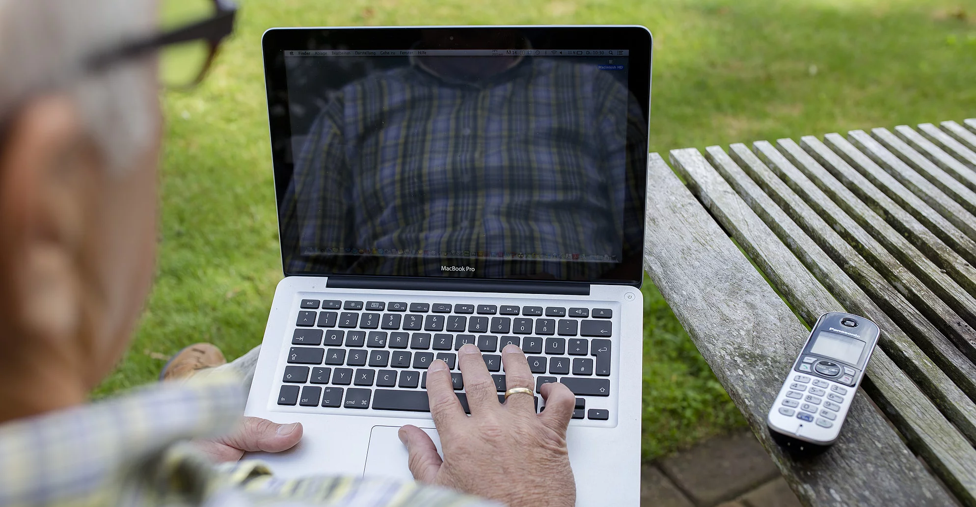 Mann am Gartentisch mit Notebook