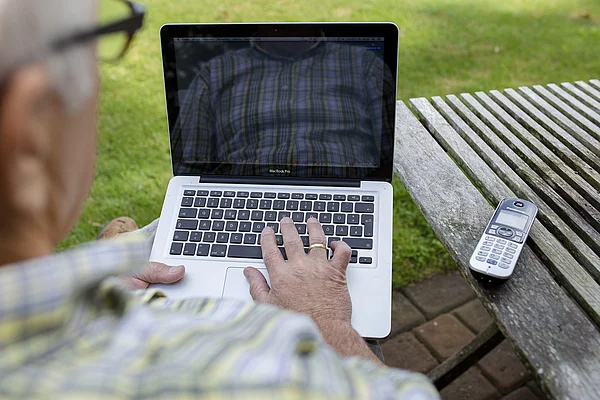 Mann am Gartentisch mit Notebook