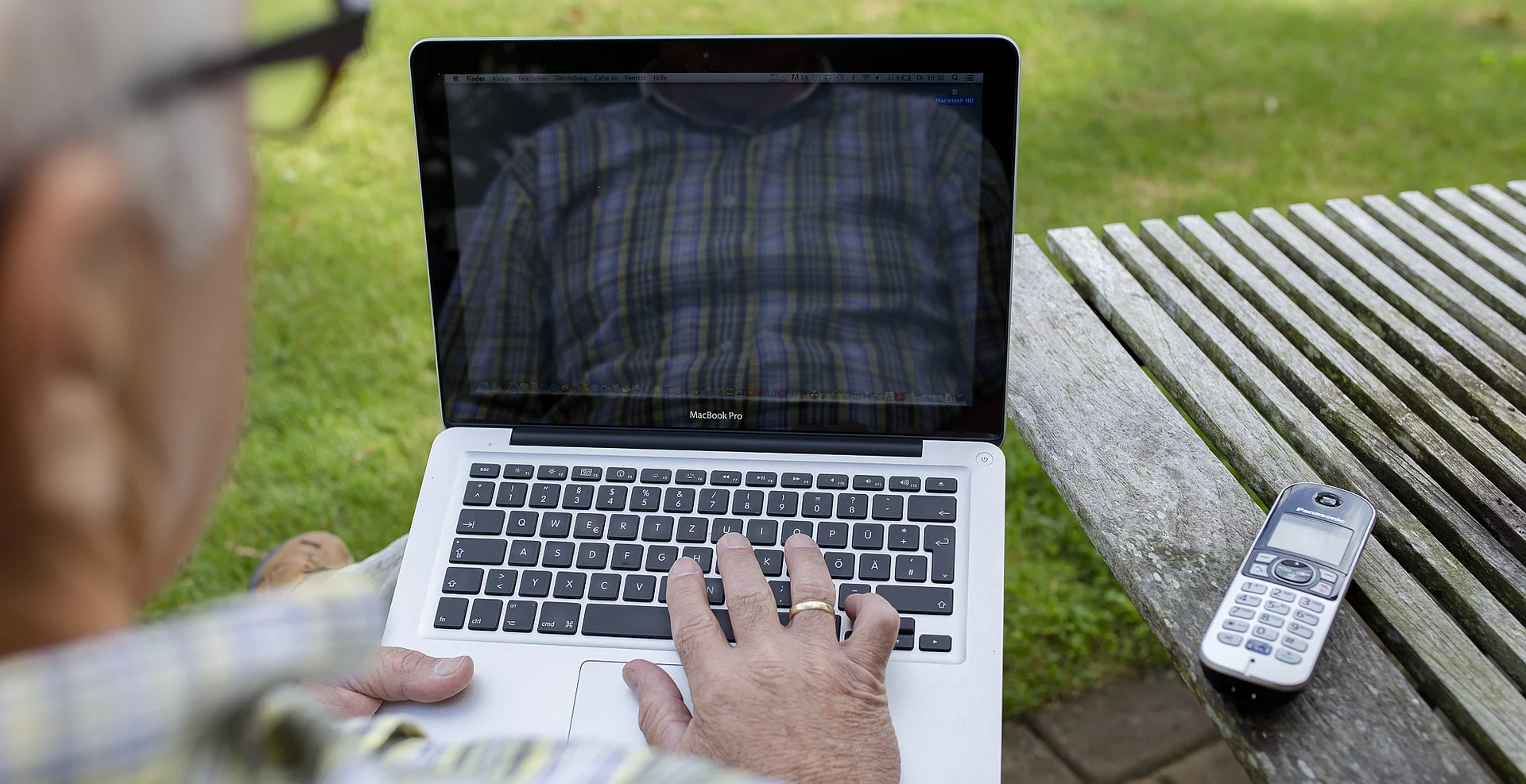 Mann am Gartentisch mit Notebook
