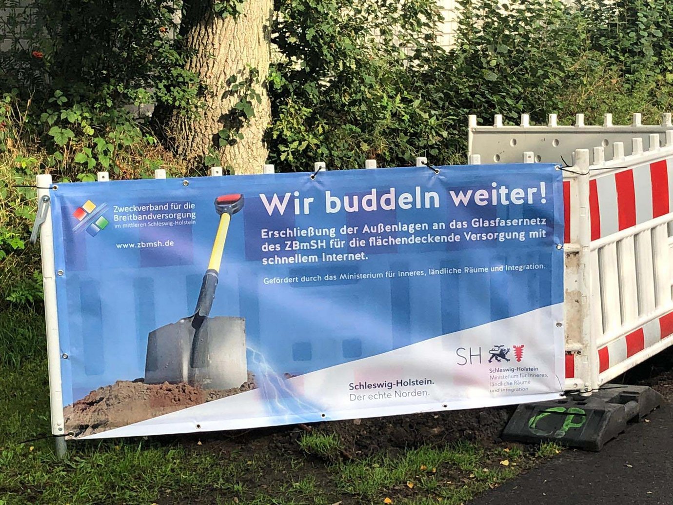 Plakat mit der Aufschrift "wir buddeln weiter" an einer Baustellenabsperrung